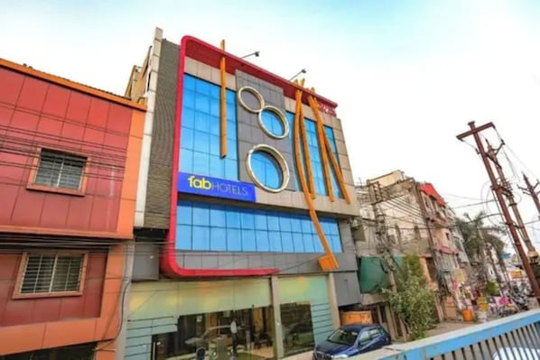 Un hotel con fachada moderna, un letrero visible que dice 'fab hotels' y un coche estacionado adelante.