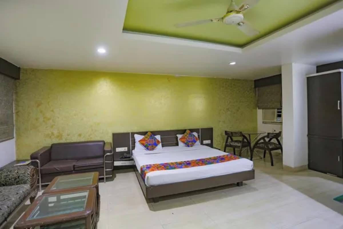 Una habitación de hotel con cama, sofá, una mesita y un ventilador de techo.