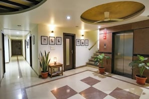 Un vestíbulo de hotel con suelo de cuadros, una escalera y plantas en macetas.