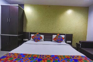 Habitación de hotel con cama, armario y cabecera con diseño geométrico.