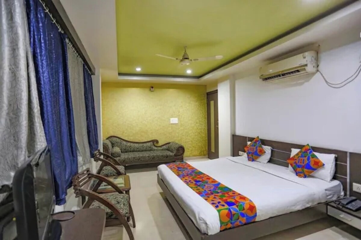 Habitación de hotel con una cama, un sofá, un escritorio y un equipo de aire acondicionado.