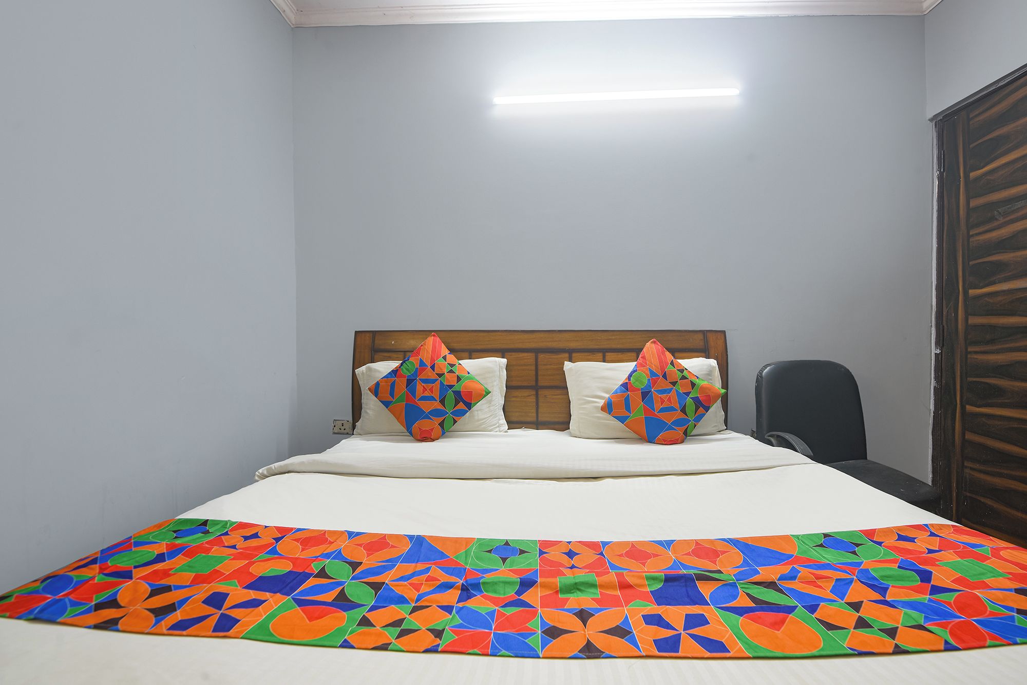 A bed with a colorful geometric-patterned bedspread and two pillows with similar designs.