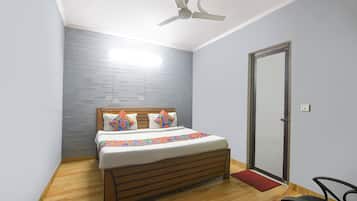 Une chambre à coucher avec un lit, un ventilateur de plafond, une porte et un paillasson rouge.