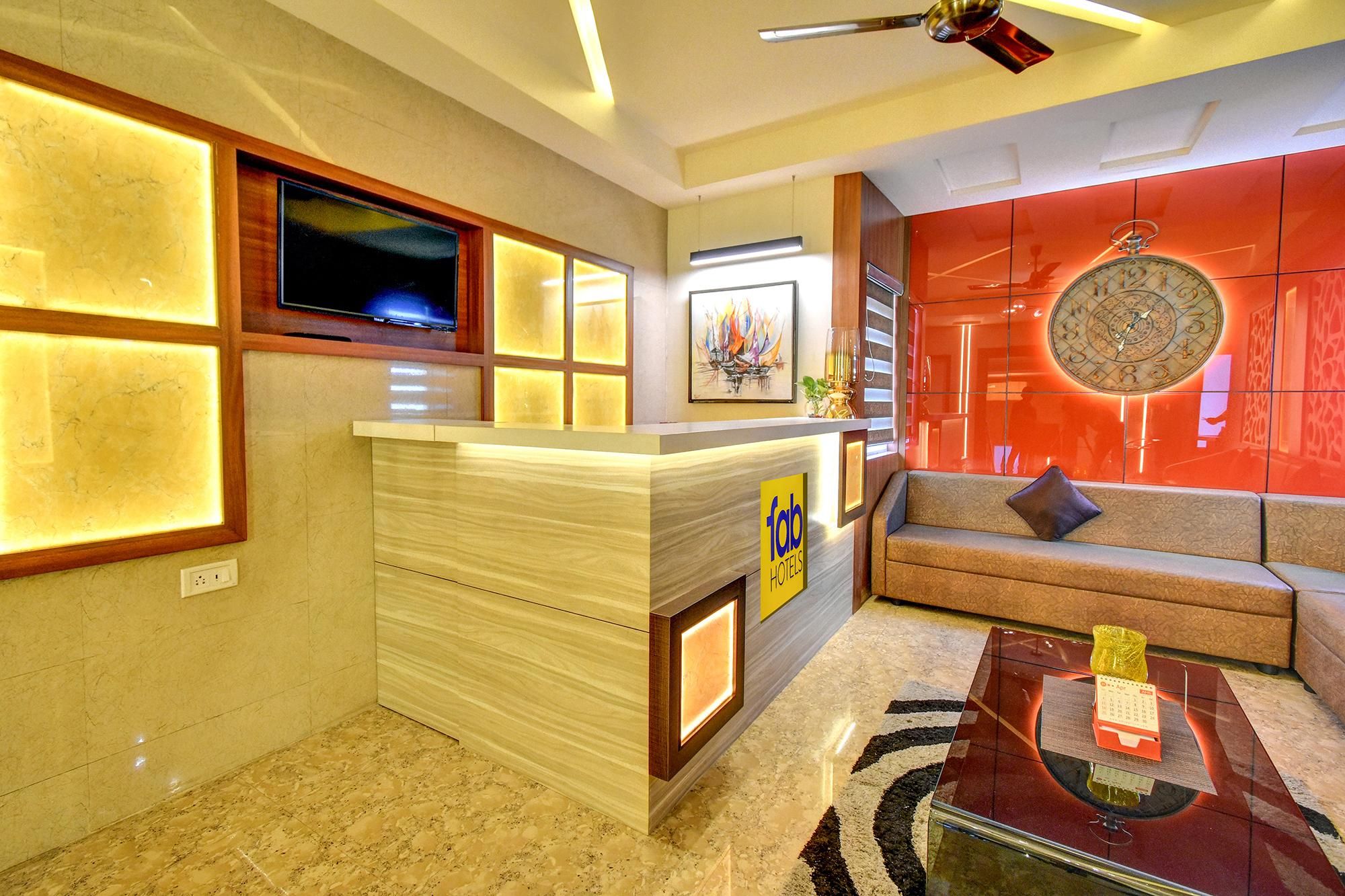 A hotel lobby with a reception desk, a sofa, a coffee table, and a wall clock.