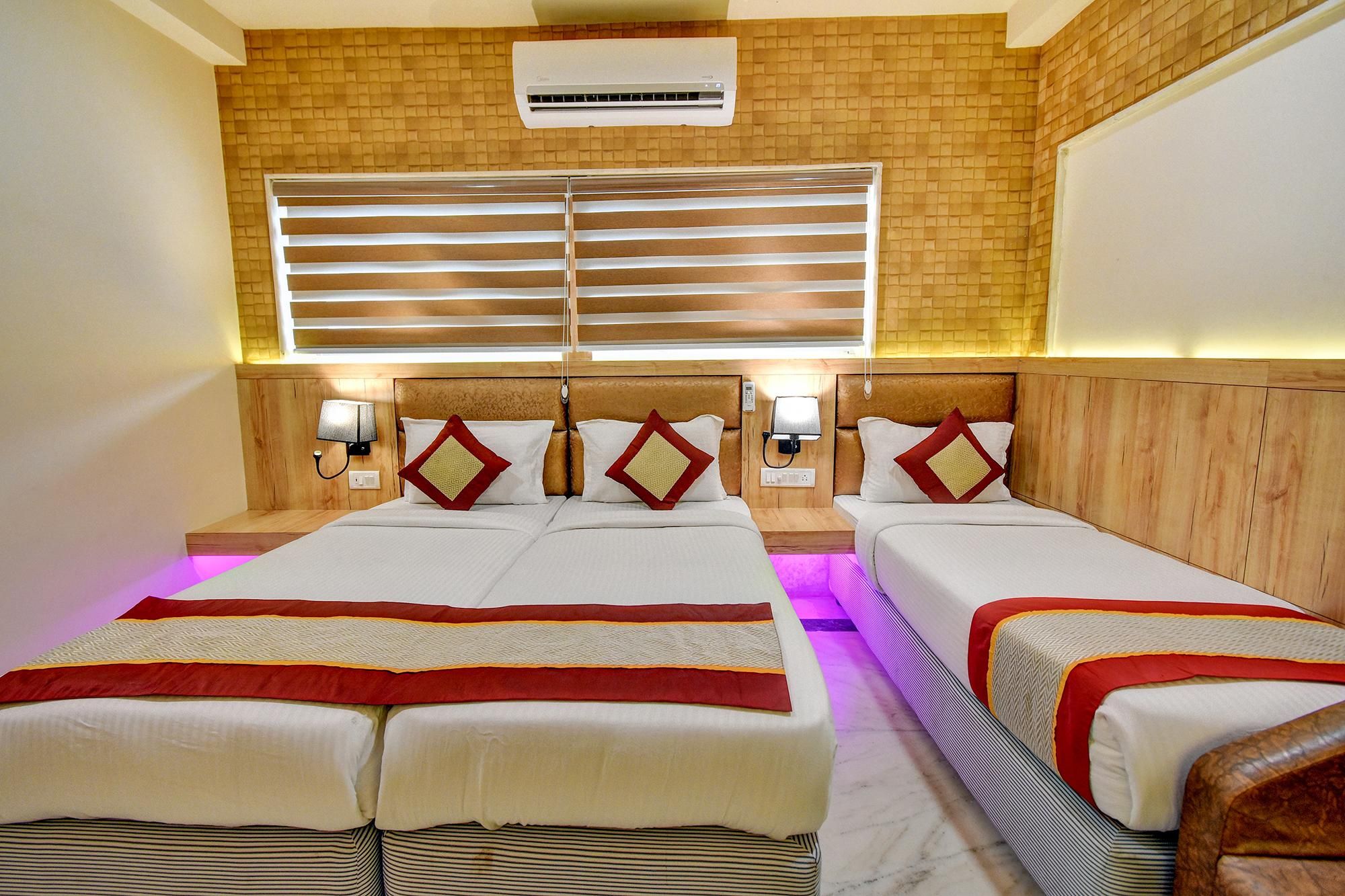 Quarto de hotel com duas camas, ar-condicionado fixado na parede e janela com persianas.