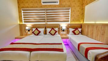 Quarto de hotel com duas camas, ar-condicionado fixado na parede e janela com persianas.