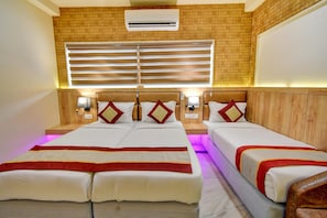 Quarto de hotel com duas camas, ar-condicionado fixado na parede e janela com persianas.