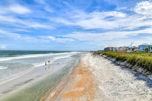 A beach with a clear sky, a sandy shore, and buildings along the coastline. - Steps to Private Beach Access, Ocean Views, Game Room, Brand New Furnishings, $300 in Free Tickets! (St. Augustine)
