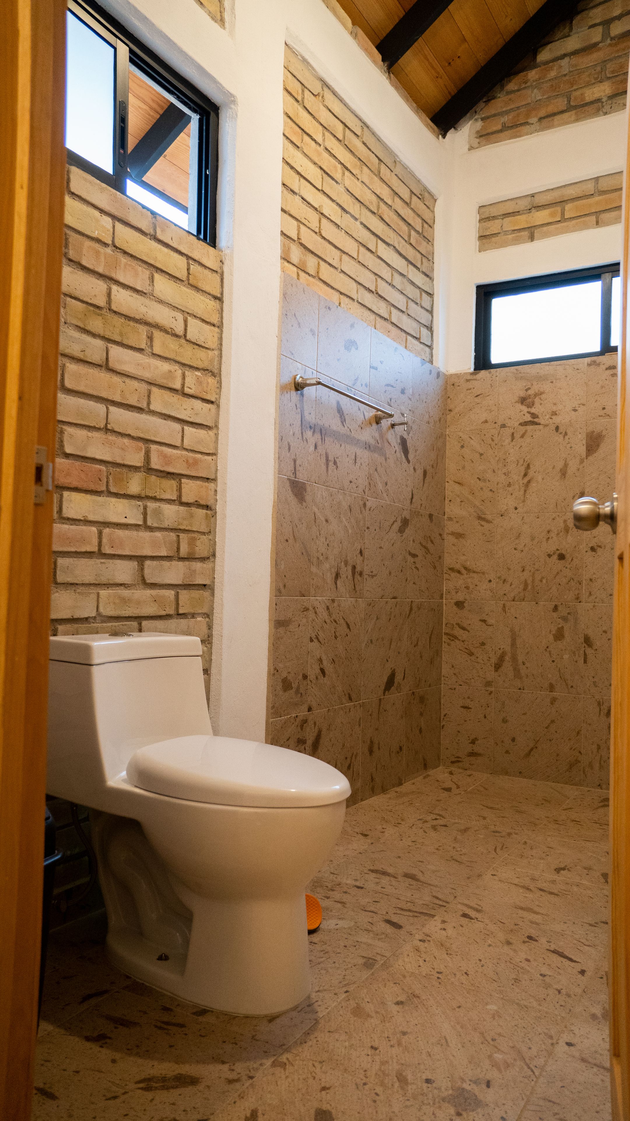 Ein Badezimmer mit Toilette, Duschbereich und Fenster.