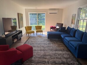 A living room with a sofa, two armchairs, a TV, and a fireplace. - Fabulous 3-bedroom house with AC in welcoming Ames (Ames)