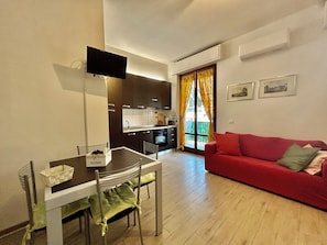 A compact living space with a dining area, kitchenette, and a red sofa. - Perosi: A Modern Loft in Florence's Novoli Neighborhood (Firenze)