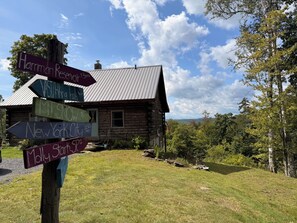 A rustic cabin with a signpost indicating directions to various destinations.