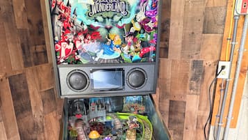 Una máquina de pinball con temática de Wonderland, que presenta una pantalla grande en la parte superior y varios elementos de juego debajo.