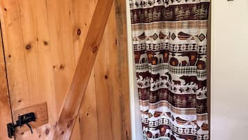 Une porte en bois avec un loquet noir, un rideau à motifs et un sol carrelé.