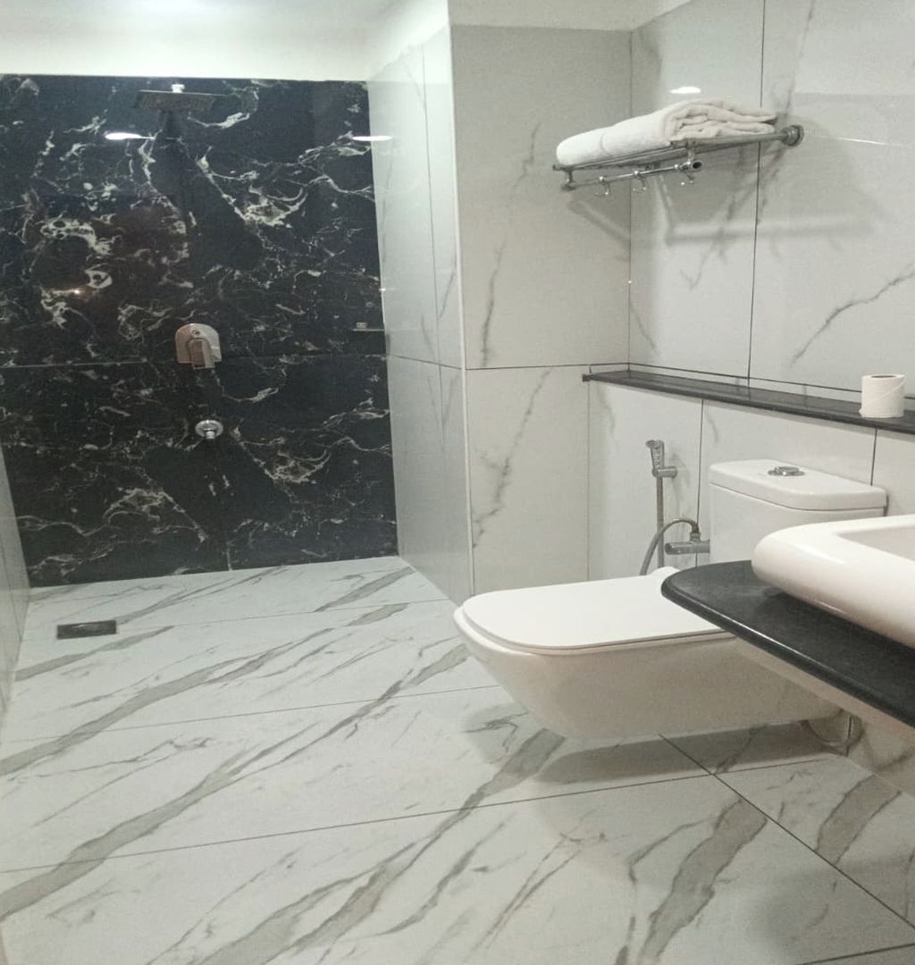 A bathroom with a marble floor, a white toilet, a glass shower enclosure, and a towel rack.