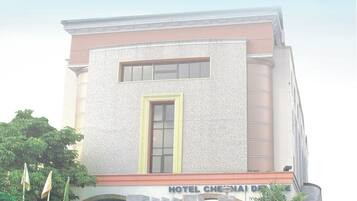A hotel with a prominent entrance, a signboard, and a well-maintained garden.