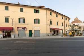 A building with a restaurant on the ground floor, a closed shuttered door, and a dome structure in the background. - A charming 67 sqm apartment with a view of the Baptistery of San Giovanni, ideal for four people. The apartment, located on the second floor of a building (NO elevator; apartment not suitable for people with disabilities: several internal steps), is situ (Pisa)