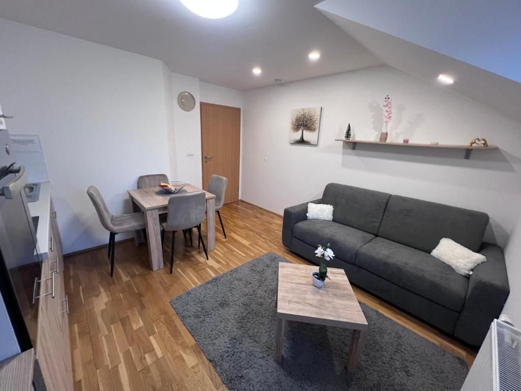 Ett modernt vardagsrum med en grå soffa, ett litet soffbord och en matplats med ett träbord och stolar.