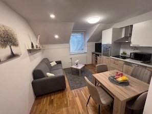 Een compacte leefruimte met een kitchenette, een eethoek en een bank.