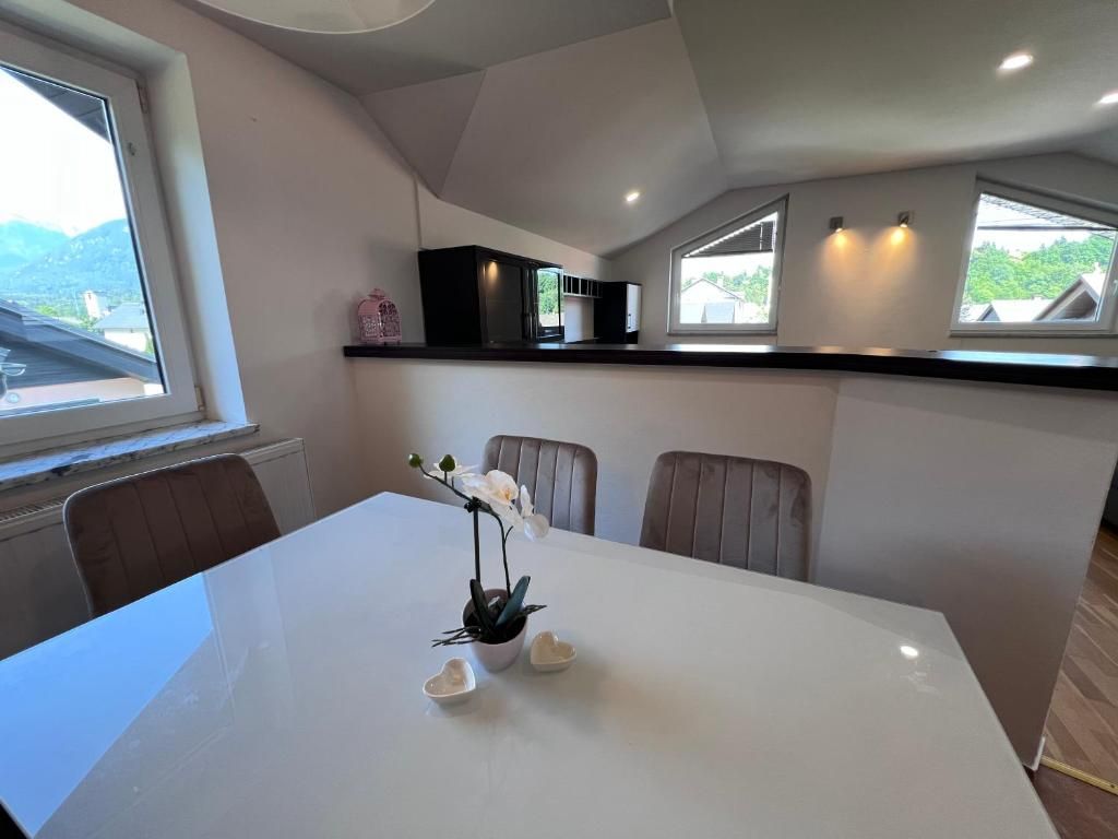 A dining area with a white table, chairs, and a potted plant.