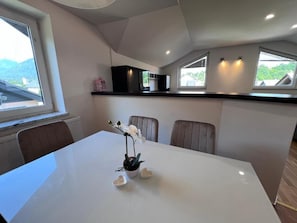 Een eethoek met een witte tafel, stoelen en een potplant.