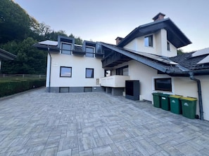 A modern building with a flat roof, multiple windows, and a paved courtyard.