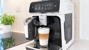 A PHILIPS coffee machine with a glass of coffee on the counter.