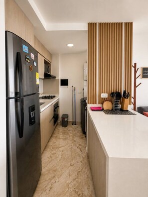 A compact kitchen with a refrigerator, stove, and microwave. - Puerto Calma | Work-Life Balance + Pool & Wi-Fi (Cartagena)