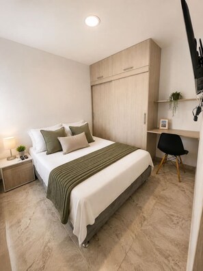 Una camera da letto con un letto, un comodino, una lampada e una scrivania con una sedia.