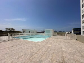 A rooftop swimming pool with a white fence, clear blue sky, and industrial buildings in the background. - Puerto Calma | Work-Life Balance + Pool & Wi-Fi (Cartagena)