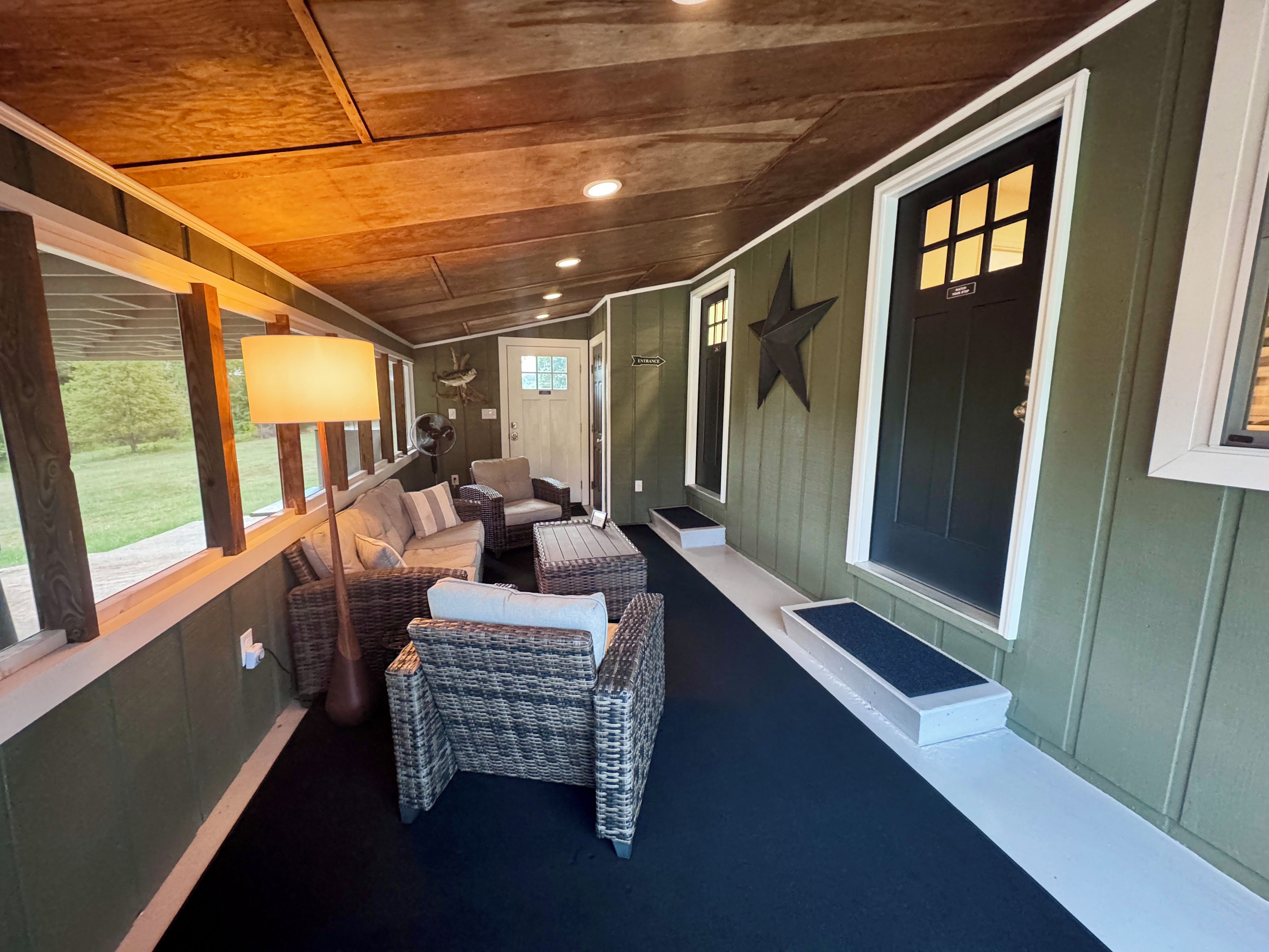 A covered porch area with wicker furniture, a lamp, and a star decoration on the wall.