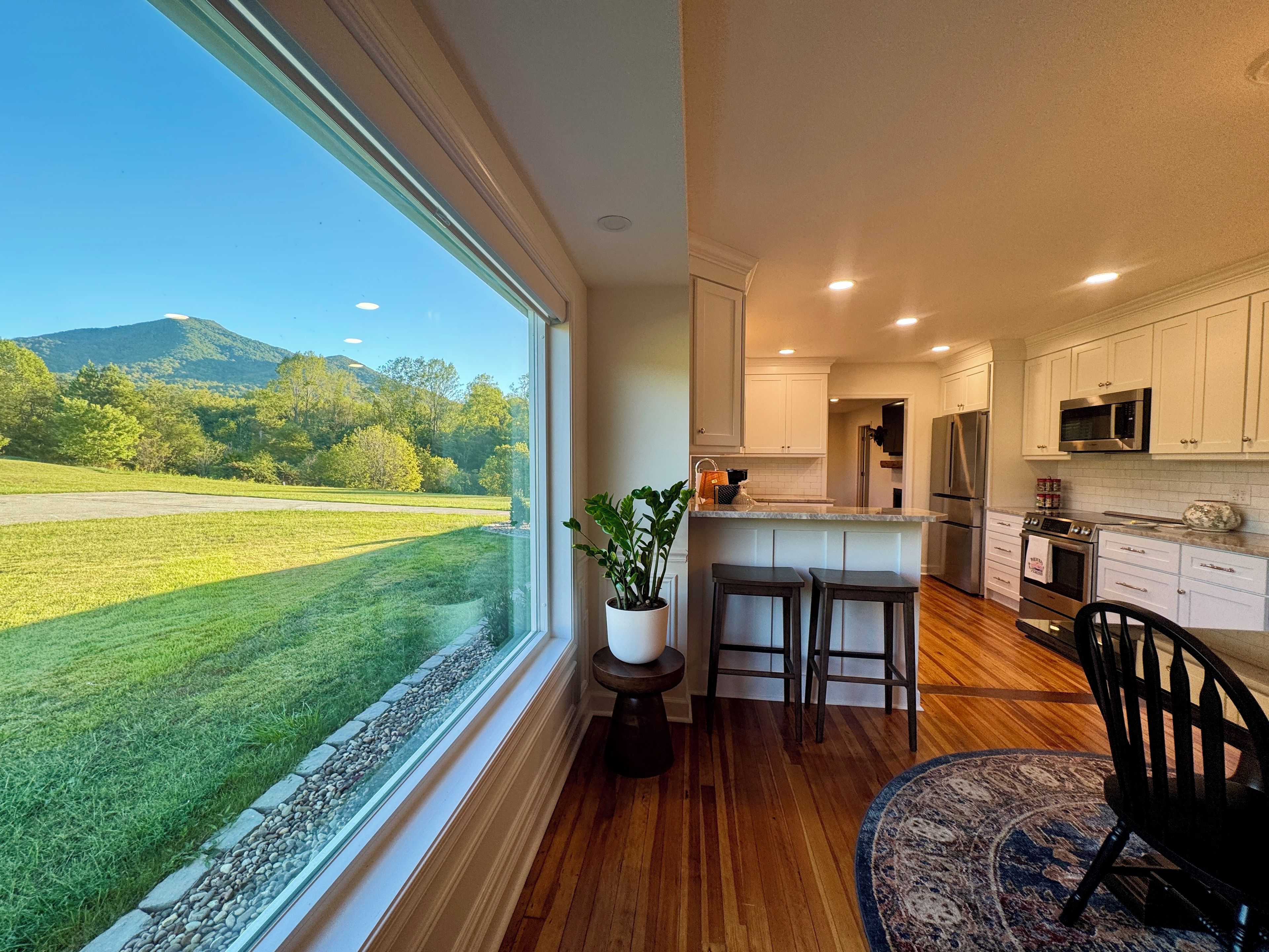Una cocina con un ventanal amplio, suelo de madera y vistas a un paisaje verde.