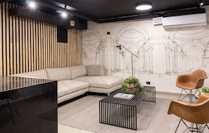 A modern living room with a sectional sofa, a black coffee table, and two chairs. - Edificio Santiago Tres by Domus Travels (Santiago)