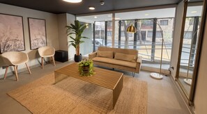 A modern living room with a sofa, two chairs, a coffee table, and a large window with a view of the street. - Edificio Santiago Tres by Domus Travels (Santiago)