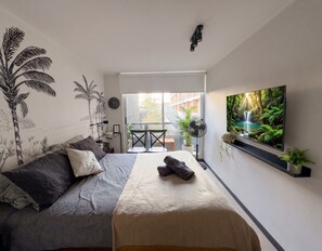 A modern bedroom with a bed, a TV mounted on the wall, and a window with a view of the outside. - Edificio Santiago Tres by Domus Travels (Santiago)