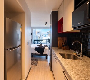 Eine moderne Küche mit einem Edelstahlkühlschrank, einer eingebauten Mikrowelle und einer Arbeitsplatte aus Granit.