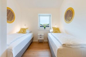 Un dormitorio con dos camas, una mesita de noche pequeña y una ventana con vistas.