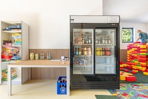 A room with a refrigerator stocked with beverages, a table with a laptop, and a colorful play area. - Ferienhaus mit Sauna und Whirlpool in Kating (Tönning OT Kating)