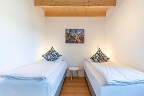 A bedroom with two single beds, a small round table, and a painting on the wall. - Ferienhaus mit Sauna und Whirlpool in Kating (Tönning OT Kating)