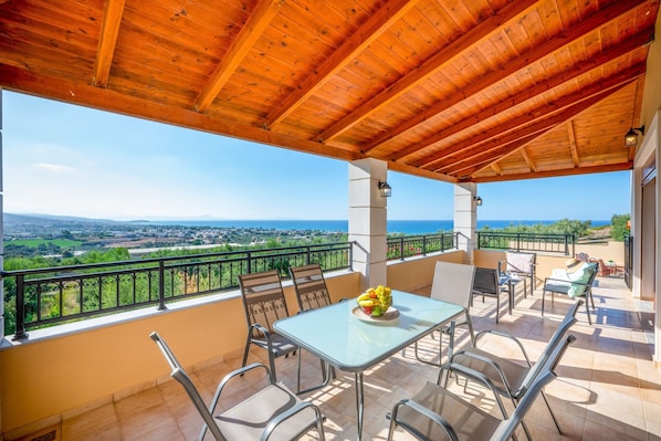 Ein überdachter Außenbereich mit Tisch und Stühlen, mit Blick auf eine reizvolle Landschaft.