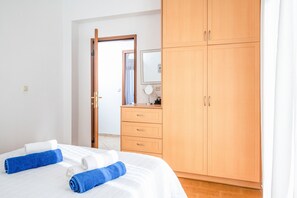 Ein Hotelzimmer mit Bett, Holzschrank, Spiegel und einem durchgegangenen Tür einsehbaren Badezimmer.