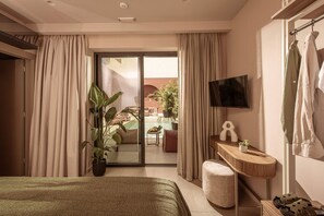 Ein Hotelzimmer mit einem Bett, einem Fernseher, einem kleinen Tisch, einer Pflanze und Blick auf einen Außenbereich mit Schwimmbad und Möbeln.