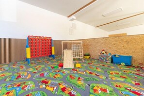 Ein Spielzimmer mit einer bunten Spielecke, einer Kletterwand und Staufächern.