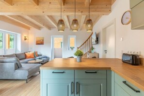 Une cuisine moderne dotée d’un plan de travail en bois, de meubles encastrés et de luminaires suspendus.