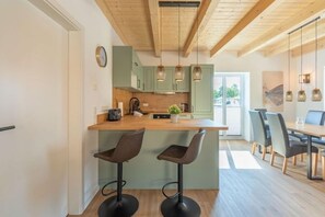 Eine moderne Küche mit einer Holztheke, Barhocker und Pendelleuchten.