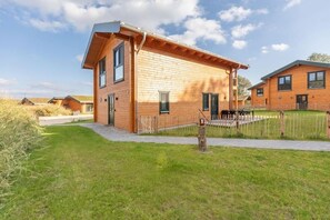 Une maison moderne en bois, dotée d’un toit plat, d’une porte d’entrée bien visible et d’un petit porche.