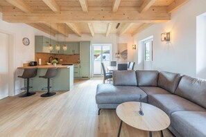 A modern living space with a kitchen, dining area, and a large sofa. - Familienferienhaus mit Sauna und Whirlpool (Tönning OT Kating)