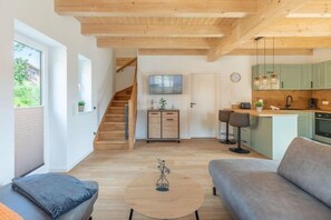 A modern living space with a staircase, a kitchen, and a seating area. - Familienferienhaus mit Sauna und Whirlpool (Tönning OT Kating)