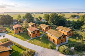 A residential area with multiple houses, each with a distinct roof and surrounded by greenery. - Familienferienhaus mit Sauna und Whirlpool (Tönning OT Kating)