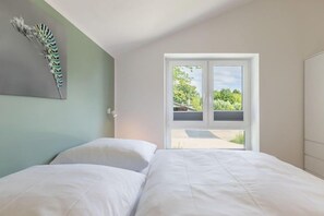 A bedroom with a bed, a door leading to a balcony, and a wall-mounted artwork. - Familienferienhaus mit Sauna und Whirlpool (Tönning OT Kating)